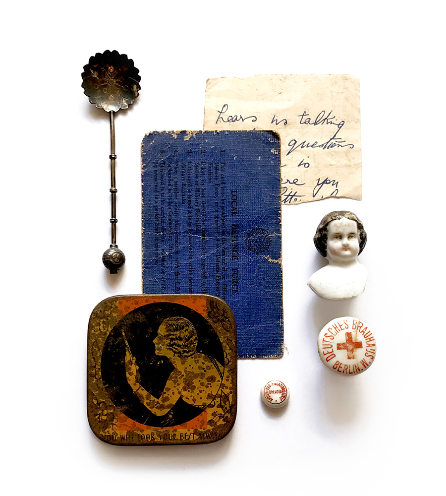 photograph of found item collage of vintage objects like a tin, spooon, doll head, hand written ephemera