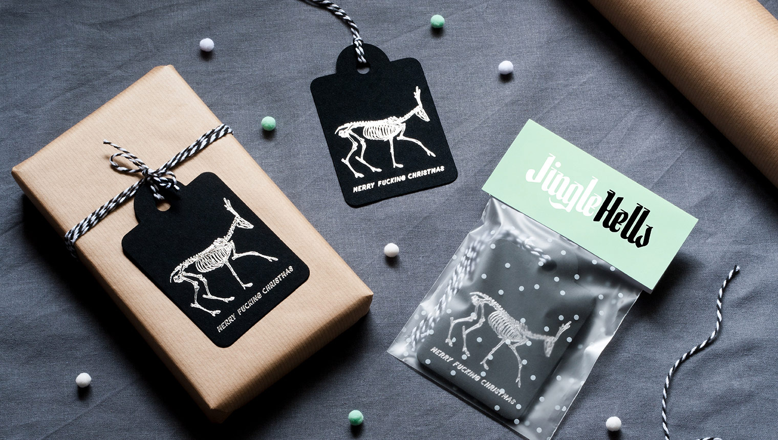 Product flaylay showing alternative foiled swingtags and packaging. The tags feature skeletons of reindeers and say 'Merry Fucking Christmas