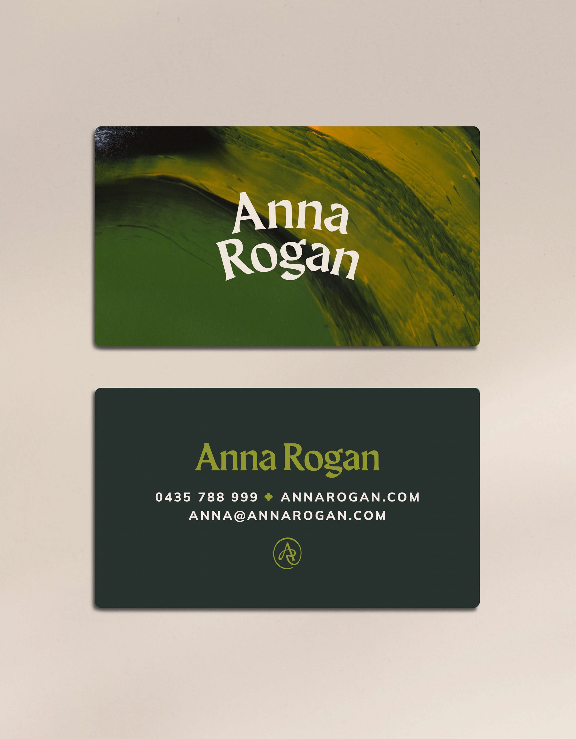 Rebranding case study image of the Anna Rogan business cards with rounded corners on a cream coloured background. The front showcases the brand paint graphic and logo while the green back showcases Anna’s details.