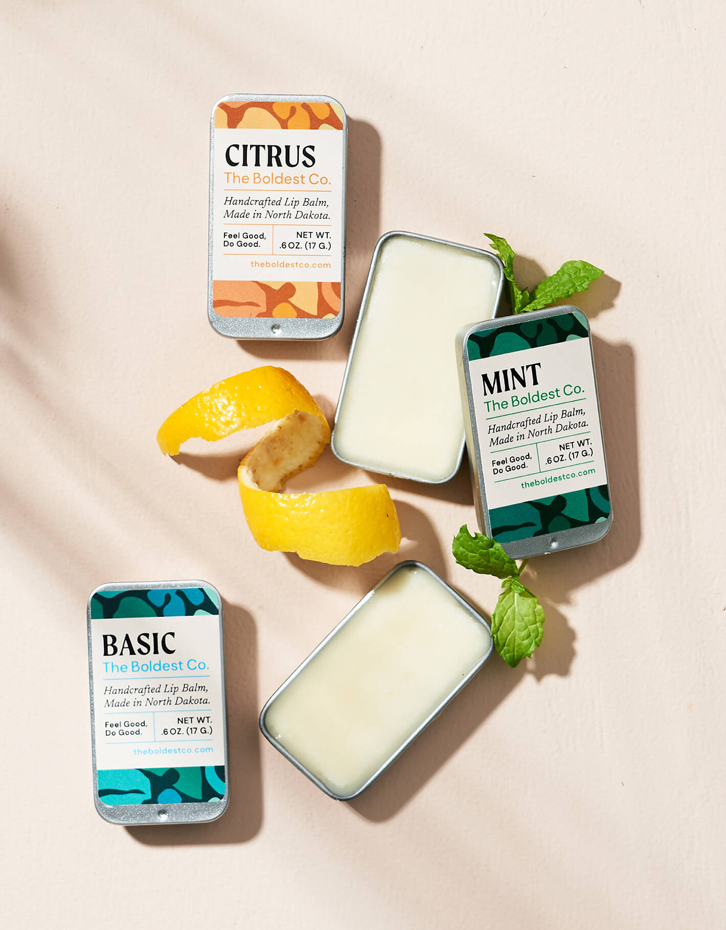 Brand design portfolio styled image of The Boldest Co’s lip-balms. The tin packaging features bright colours and mid-century inspired design and are surrounded by decorative lemon and mint garnishes.